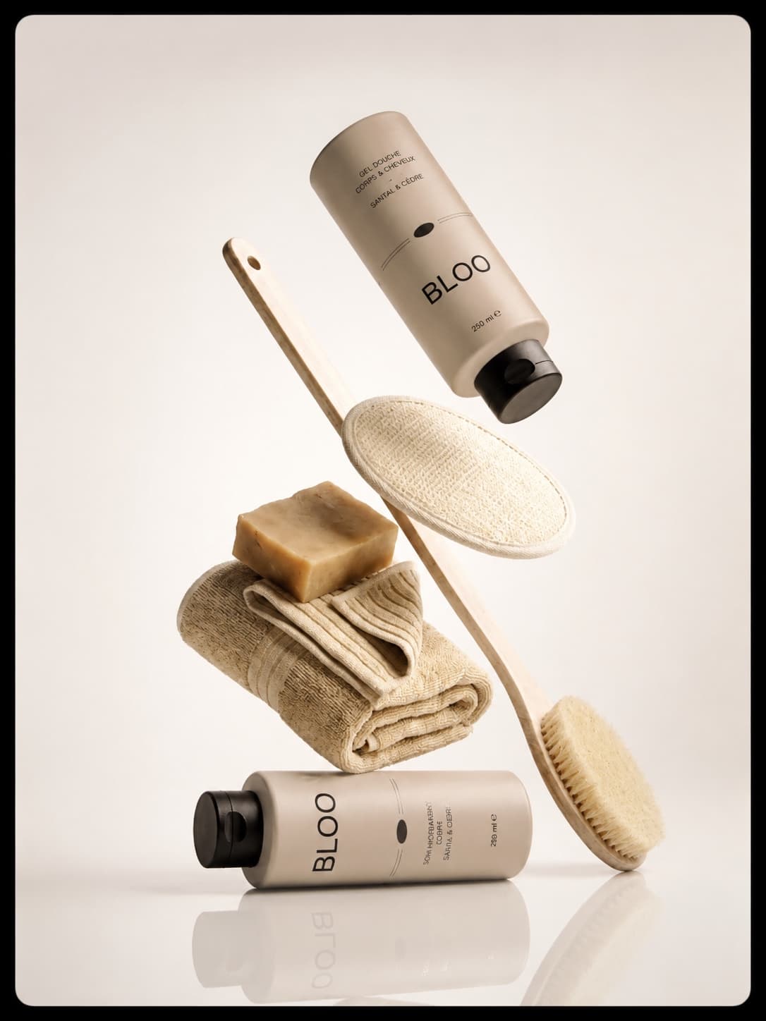 Concept publicitaire : gel douche BLOO, savon artisanal et serviettes en tons beiges sur fond clair.